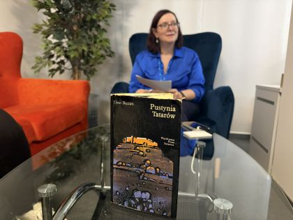 Marcowe spotkanie Klubu Książki "UGryź Książkę" - relacja. Na zdjęciu na pierwszym planie okładka książki "Pustynia Tatarów", w tle osoba prowadząca klub: Monika Budzińska