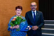 Dyrektor Biblioteki Grażyna Jaśkowiak z bukietem kwiatów i medalem, obok Rektor UG Piotr Stepnowski