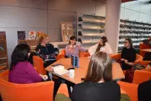 Spotkanie Klubu Książki: przy stole siedzi grupa osób i dyskutuje nt. książki "Tysiąc okrętów"