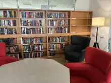 Nowy kącik beletrystyczny w Bibliotece Ekonomicznej. Na zdjęciu są regały z książkami, wokół wysokie fotele i lampa. 