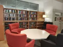Nowy kącik beletrystyczny w Bibliotece Ekonomicznej. Na zdjęciu są regały z książkami, wokół wysokie fotele i lampa. 
