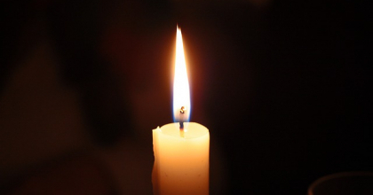 Paląca się biała świeca na czarnym tle - nekrolog 